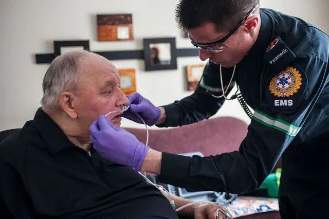 A paramedic assesses a palliative care patient in the comfort of their home. The program means Pancreatic Cancer patients spend less time outside of hospital. 