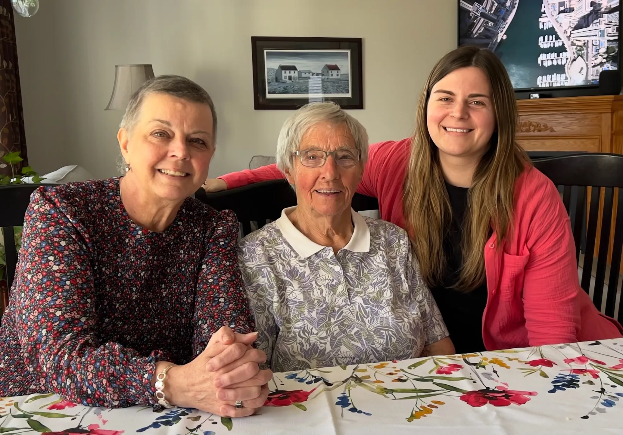 Three generations of women sharing a warm moment at a table with a floral tablecloth, representing the heart of pancreatic cancer advocacy.
