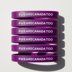 Three purple #WeAreCanadaToo wristbands on a white surface, promoting affordable advocacy for healthcare access.